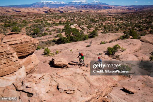 a man leads a woman on a cross-country mountain bike trail ride in moab, utah, usa. - red rock formation stock pictures, royalty-free photos & images