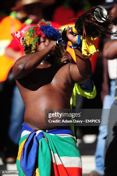 Football fan blows a vuvuzela in the stands.