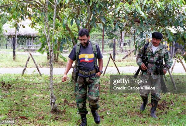 Alfonso Cano, the second in command of The Revolutionry Armed Forces of Colombia, FARC walks across his FARC compound accompanied by a bodyguard.