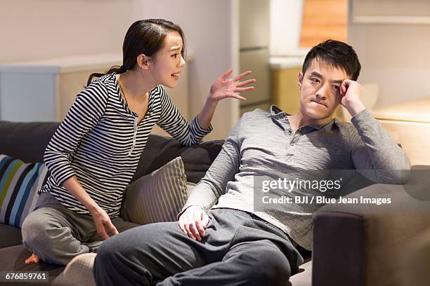 young couple arguing on living room sofa - asian couple arguing stockfoto's en -beelden