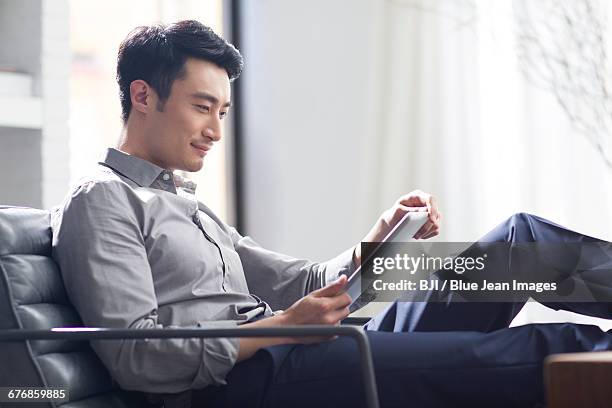 young man using digital tablet in office - wealthy asian man stock pictures, royalty-free photos & images