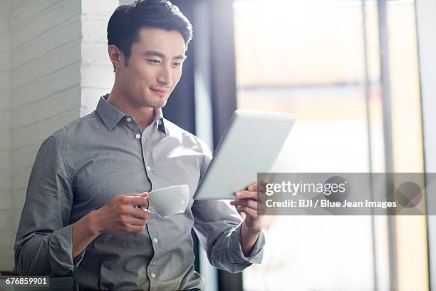 young man using digital tablet - östasiatiskt ursprung bildbanksfoton och bilder