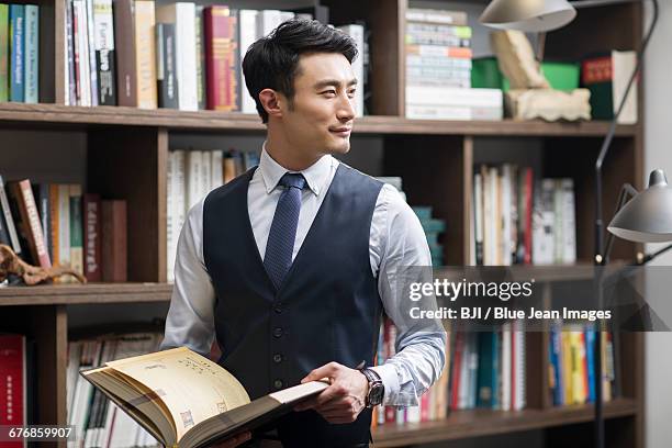 young businessman reading book in his study - vest stock-fotos und bilder