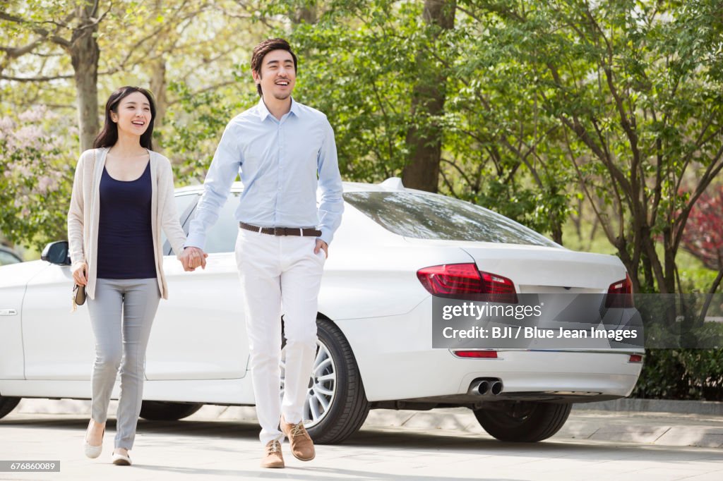 Happy young couple holding hands walking