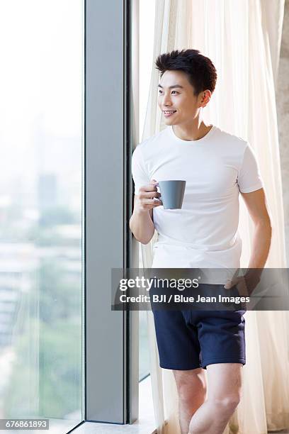 young man drinking coffee at home - short sleeved 個照片及圖片檔