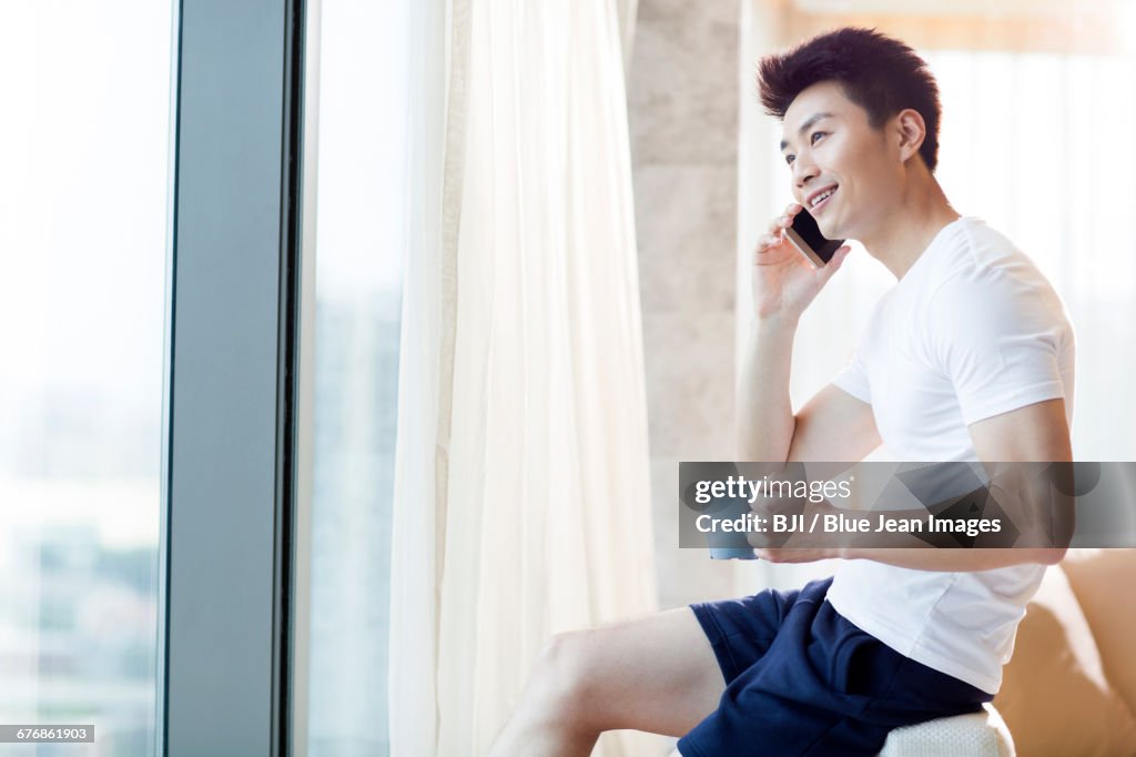 Young man talking on cell phone at home