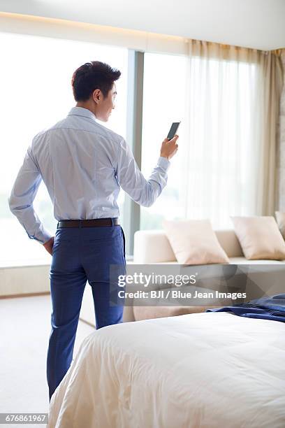 young businessman using smart phone at home - back cushion stock pictures, royalty-free photos & images
