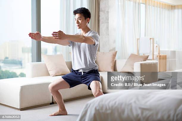 young man exercising at home - かがむ 人 横 ストックフォトと画像
