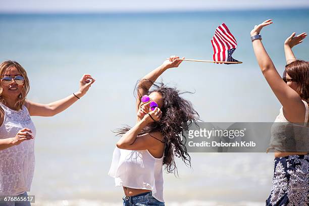 three adult female friends waving american flag on beach, malibu, california, usa - american flag ocean stock pictures, royalty-free photos & images