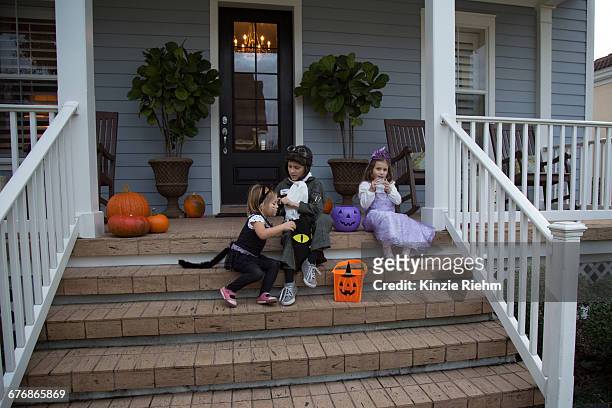 brother and sisters trick or treating on porch stairway - cat costume stock pictures, royalty-free photos & images
