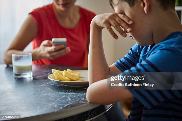boy at dining table, hand on eyes looking upset - parental authority stock pictures, royalty-free photos & images