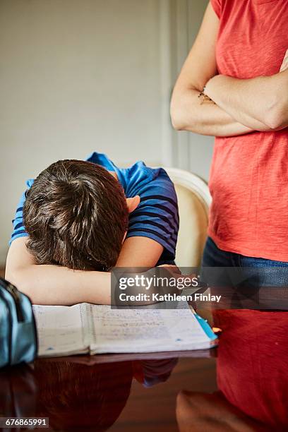 mother standing by upset son doing homework - strict parent stockfoto's en -beelden