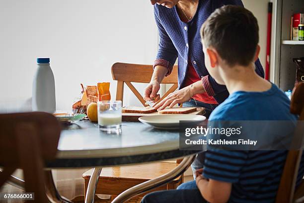 mother making son sandwich - een broodje smeren stockfoto's en -beelden