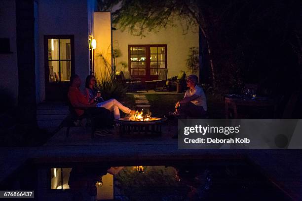 mature adults relaxing by patio fire at dusk - buraco de fogueira imagens e fotografias de stock