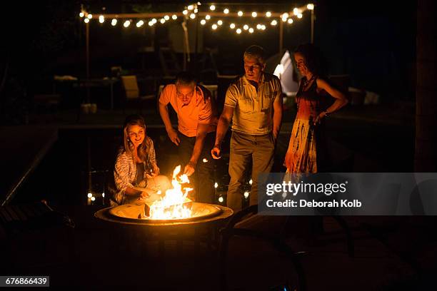 mature adult couples toasting marshmallows on patio fire at night - hot summer nights film stock-fotos und bilder