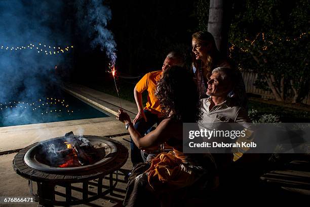 mature adult couples watching sparkler by patio fire at night - hot latin nights stock pictures, royalty-free photos & images