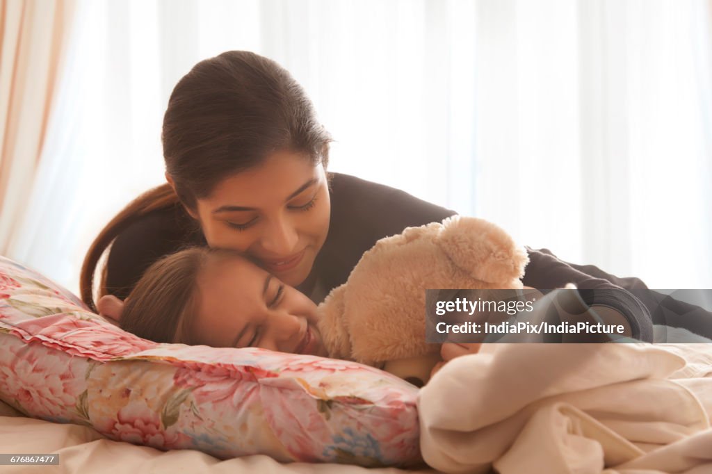 Mother comforting daughter in bed