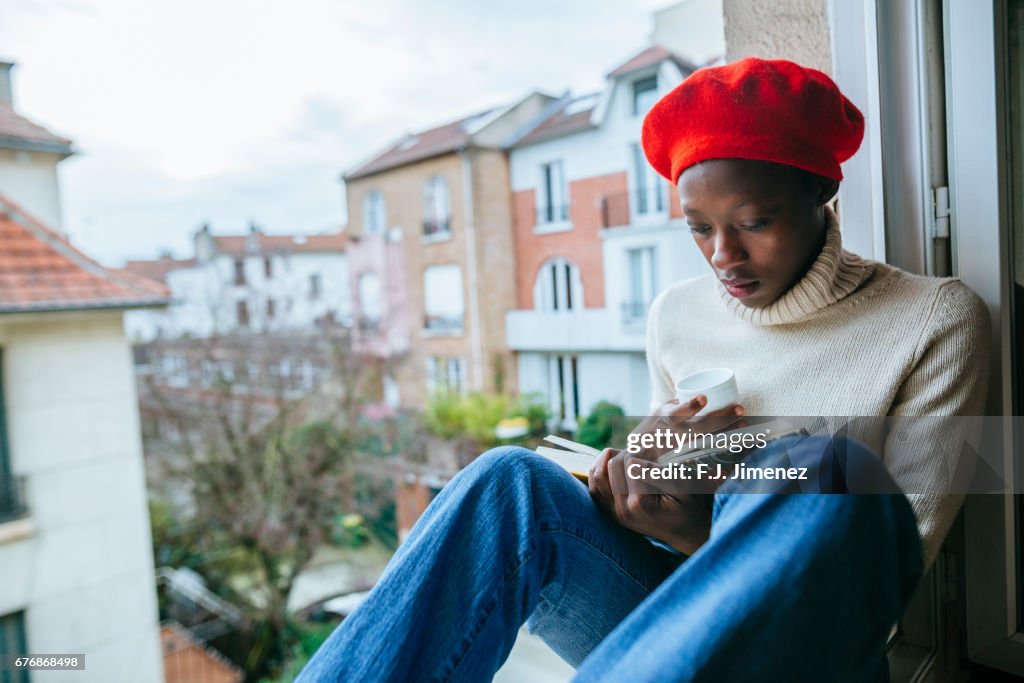 Young woman sitting on window reading