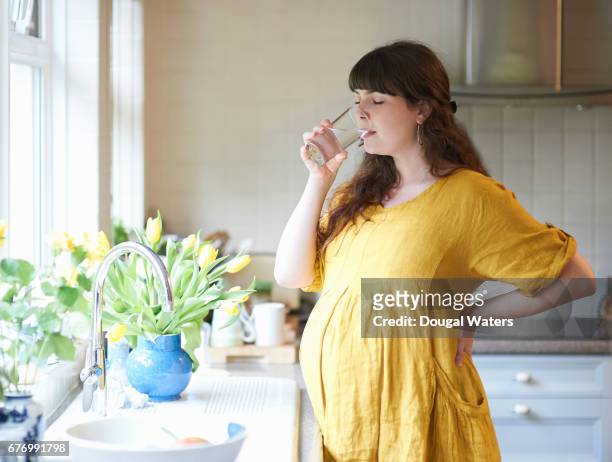pregnant woman drinking glass of water in kitchen at home. - dougal waters 個照片及圖片檔
