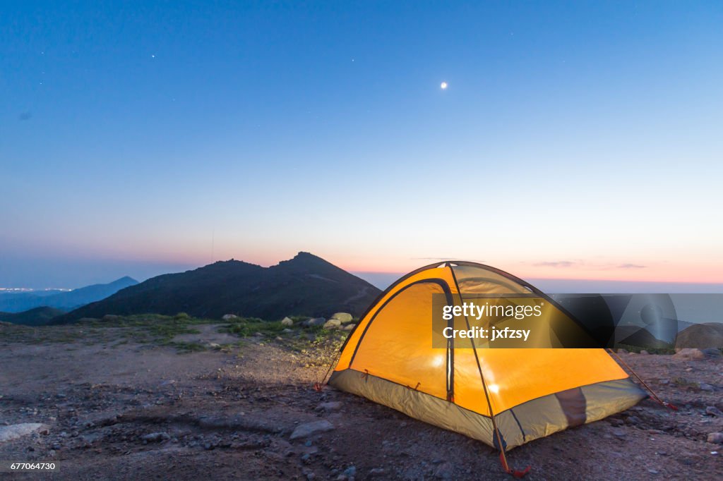 Camp tent with light on under sky