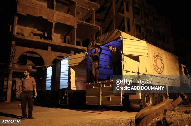 People prepare to unload supplies from a Syrian Arab Red Crescent truck part of a SARC and UN aid convoy in the rebel-held town of Douma, on the...