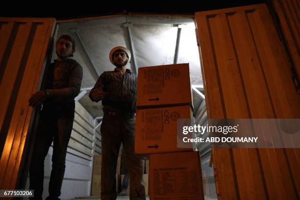 People unload supplies from a Syrian Arab Red Crescent truck part of a SARC and UN aid convoy in the rebel-held town of Douma, on the eastern...