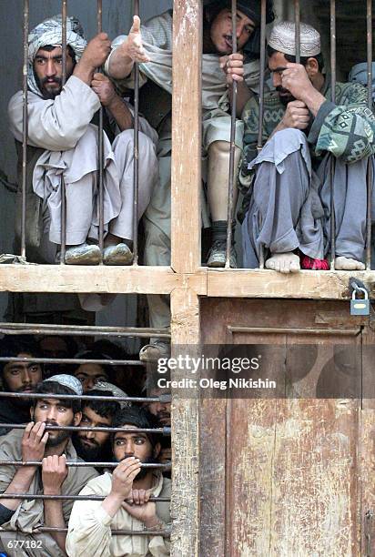 Former Taliban fighters, who surrendered to the Northern Alliance following their defeat in Kunduz a week ago, gather at a window to the courtyard of...