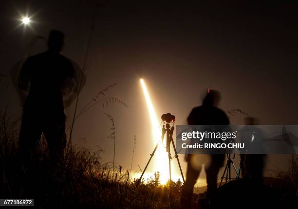 Photographers take pictures of a streak of light trailing off into the night sky as the US military test fires an unarmed intercontinental ballistic...