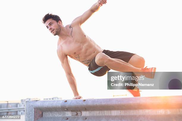 topless young men jumping over obstacle - philipp nemenz foto e immagini stock