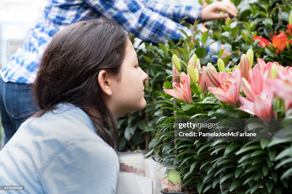 Young Eurasian Woman Smelling Potted Liliy Flowers at Garden Centre