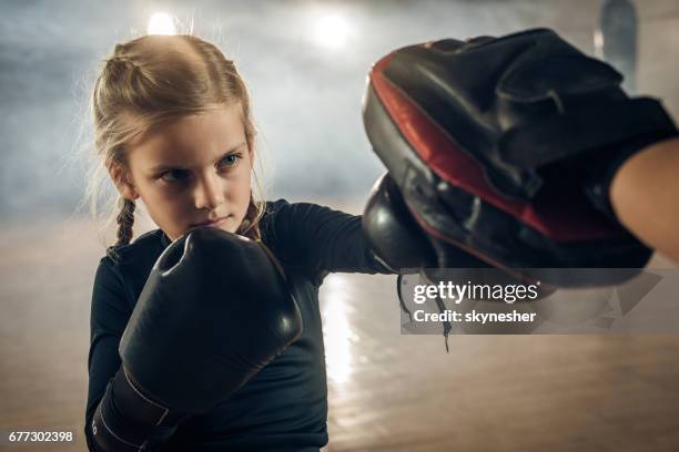 niña ejercicio de boxeo con el entrenador irreconocible en un club de salud. - kick boxing fotografías e imágenes de stock