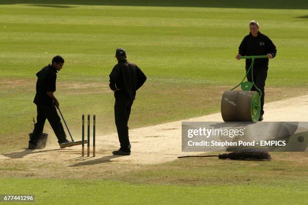 Ground staff use a roller on the wicket