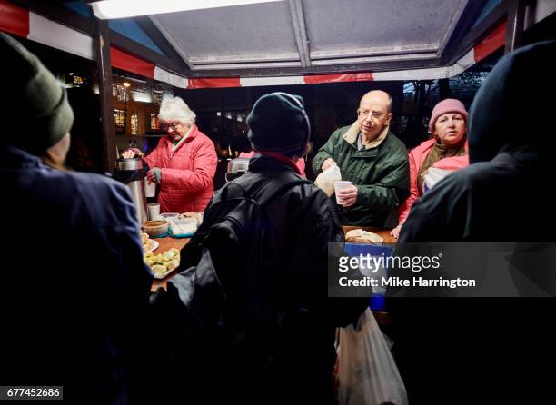 group of volunteers serving food and drinks at soup kitchen for the homeless - soup kitchen stock-fotos und bilder