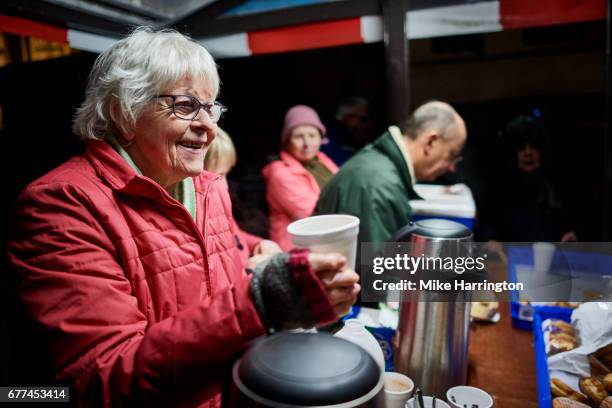 mature female serving a hot drink at local soup kitchen - homelessness stockfoto's en -beelden