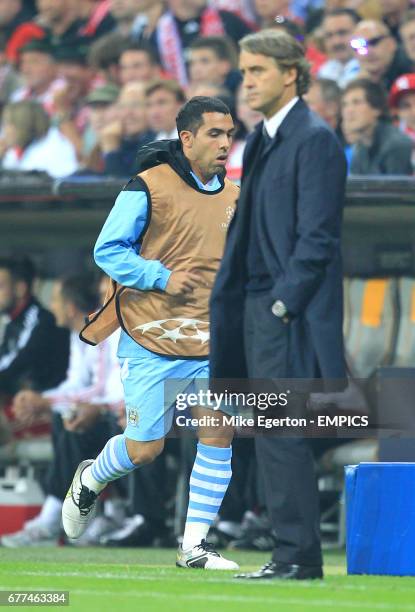 Manchester City's Carlos Tevez runs past manager Roberto Mancini on the touchline