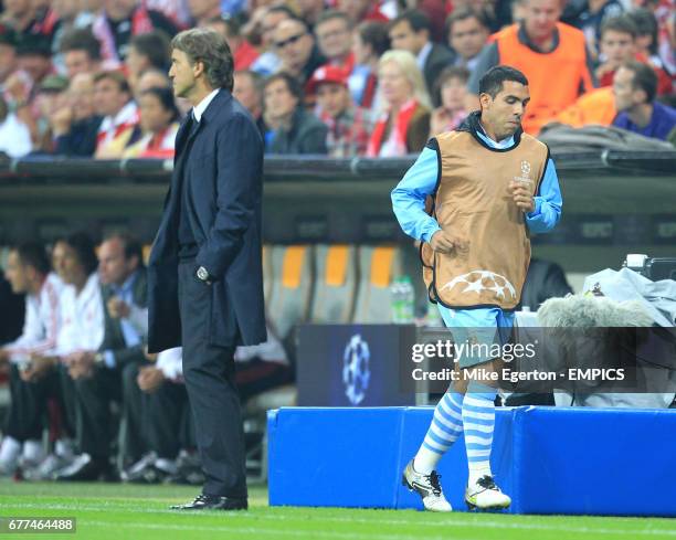 Manchester City's Carlos Tevez runs past manager Roberto Mancini on the touchline