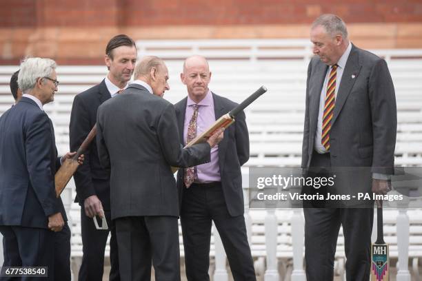 The Duke of Edinburgh is shown a number of bats by cricket journalist Simon Hughes , and former England cricketer Angus Fraser , during a visit to...