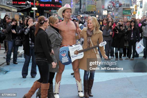 Group of women posing with a Naked Cowboy street performer in Times Square.