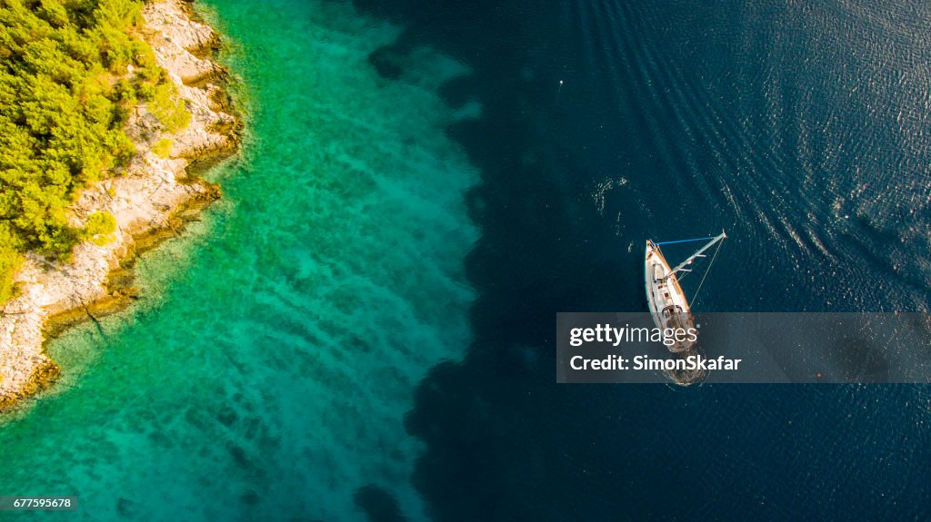 Tourists swimming by the sailboat