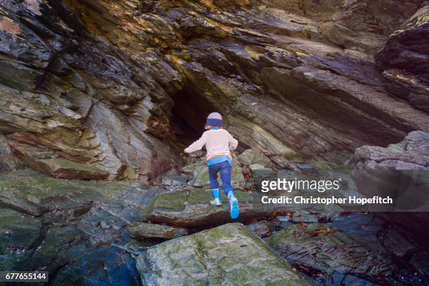 young boy exploring coastal cave - cave stock pictures, royalty-free photos & images