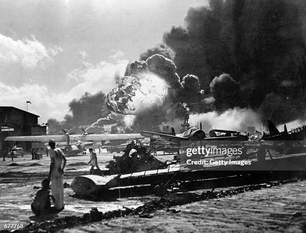 Sailors stand amid wreckage watching as the USS Shaw explodes December 7, 1941 on Ford Island, Pearl Harbor, Hawaii during the Japanese attack....