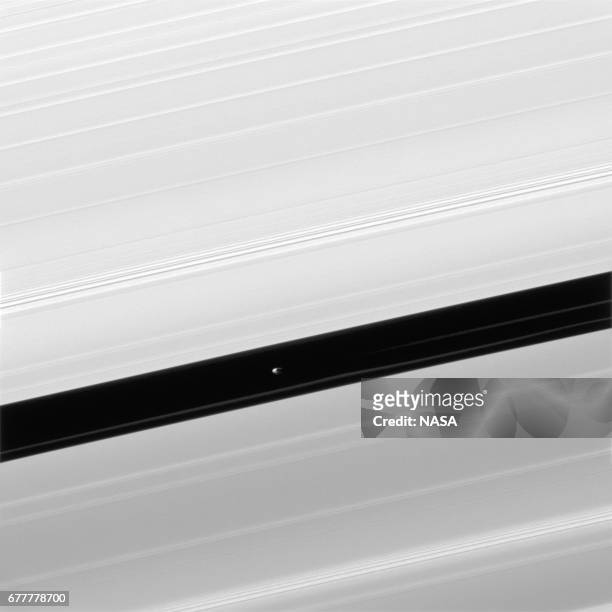 In this handout image provided by the National Aeronautics and Space Administration , Pan, seen in image center, maintains the Encke Gap in which it...