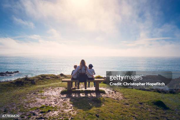 mother and young sons resting on a bench - cornwall england imagens e fotografias de stock