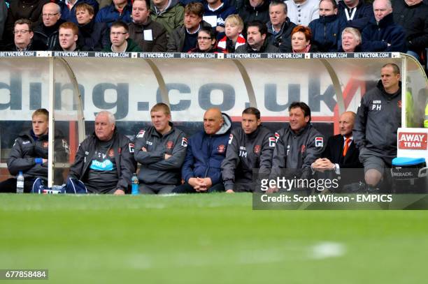 Blackpool manager Ian Holloway watches the action from the dug out with members of his back room staff