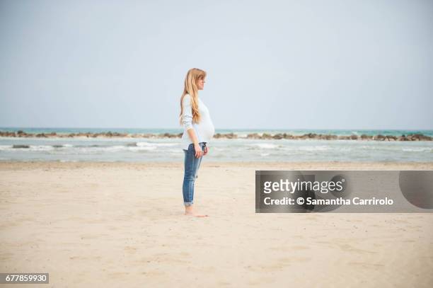 pregnant woman on the beach. casual clothes. - ambientazione tranquilla stockfoto's en -beelden