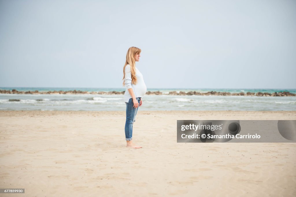 Pregnant woman on the beach. Casual clothes.