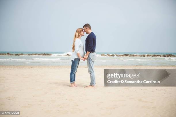 pregnant couple on the beach. hand in hand. casual clothes. - romanticismo 個照片及圖片檔