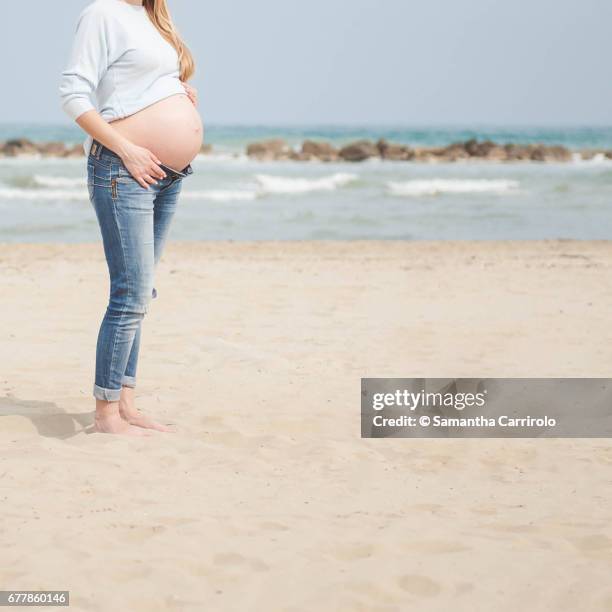 pregnant woman on the beach. casual clothes. nude abdomen. - caucasico stock-fotos und bilder