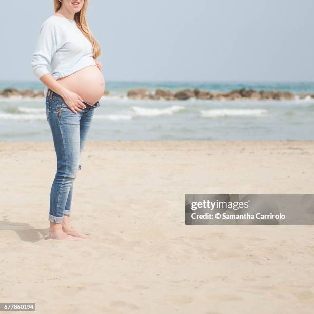 pregnant woman on the beach. casual clothes. nude abdomen. - serenità stockfoto's en -beelden