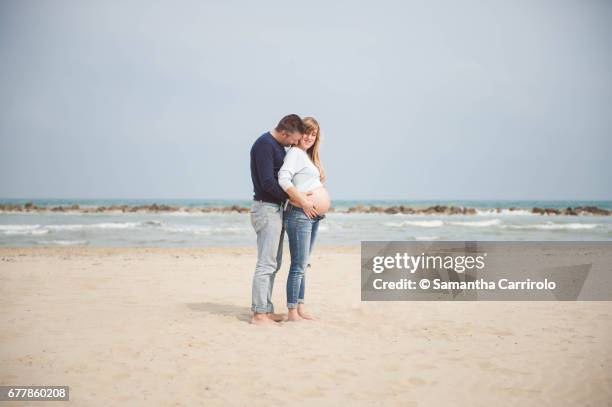 pregnant couple on the beach. hands on the belly. embrace. casual clothes. - serenità imagens e fotografias de stock